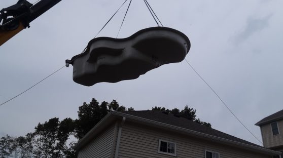 Pool form being lowered into backyard