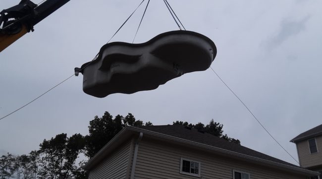 Pool form being lowered into backyard